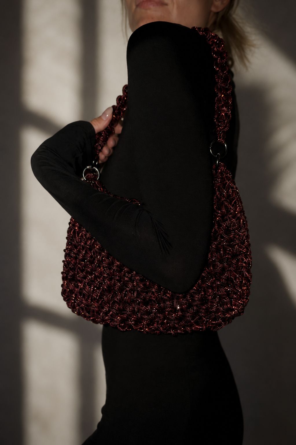 Handcrafted rhinestone cord macrame bag in a deep Red Wine burgundy shade held by a model in a black outfit.